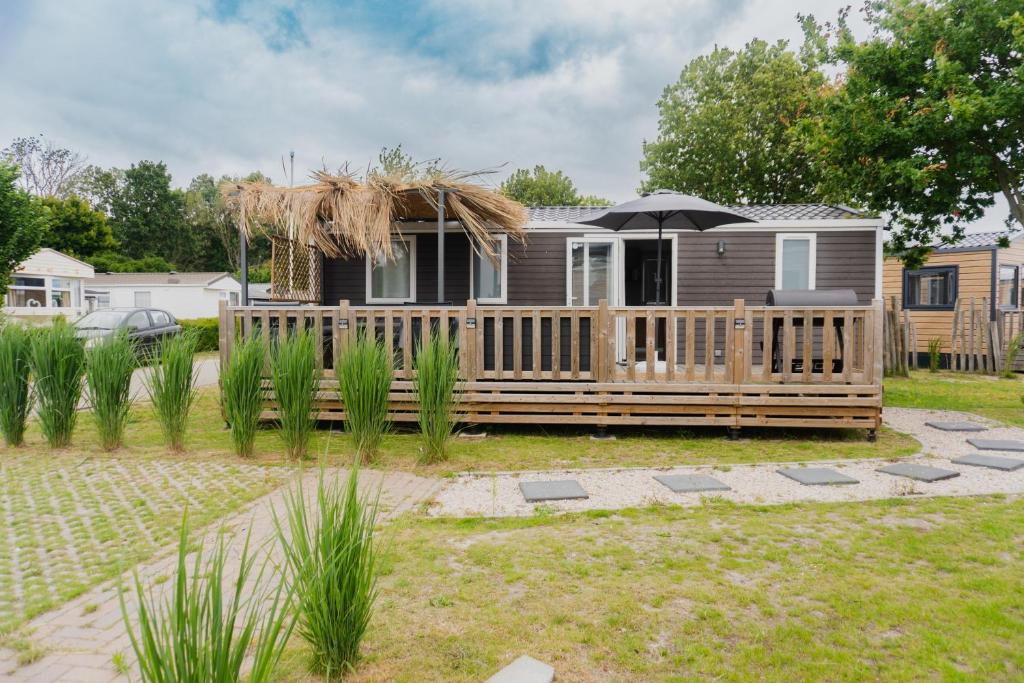 a house with a deck with an umbrella at Moderne chalet op het strand in Kropswolde