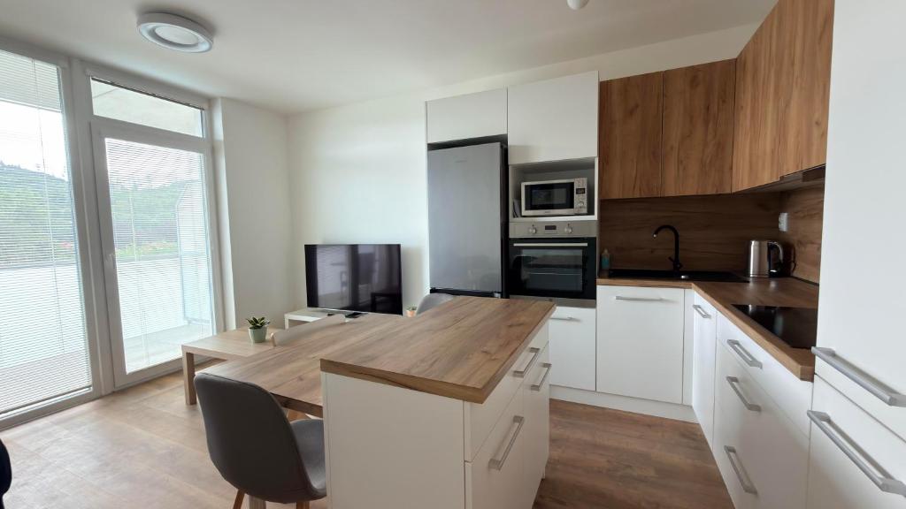 a kitchen with white cabinets and a wooden counter top at Moderní apartmán Boskovice in Boskovice