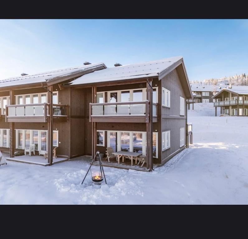 a house in the snow with a mop in front of it at Bualie leilighet in Gol