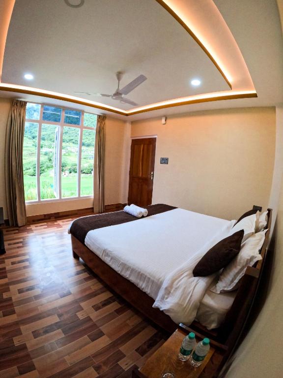 a bedroom with a large bed and a large window at Taleries Stays in Dirang Dzong