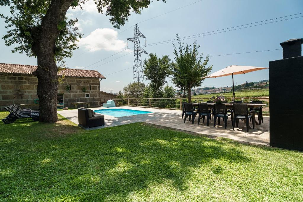 a garden with a table and chairs and a pool at Quinta de Carvalhal - Casa da Vinha in Guimarães