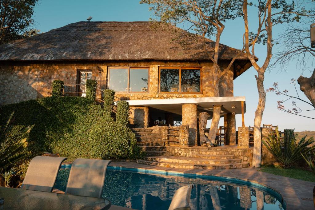 a house with a thatched roof next to a pool at Masumu River Lodge in Binga