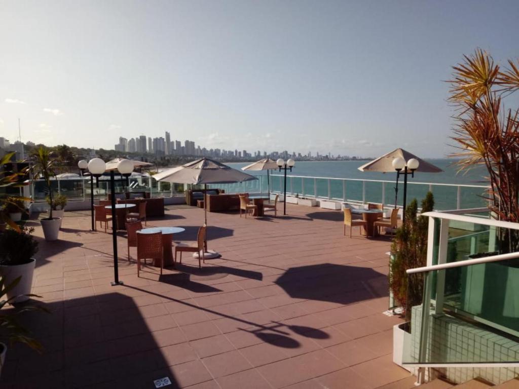 a patio with tables and chairs next to the water at Blue Sunset Experince - Cabo Branco in João Pessoa
