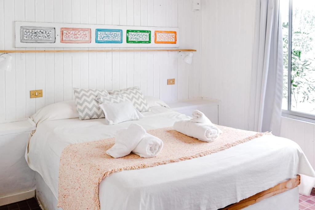 a white bedroom with two towels on a bed at La Posada del Abra in Tigre