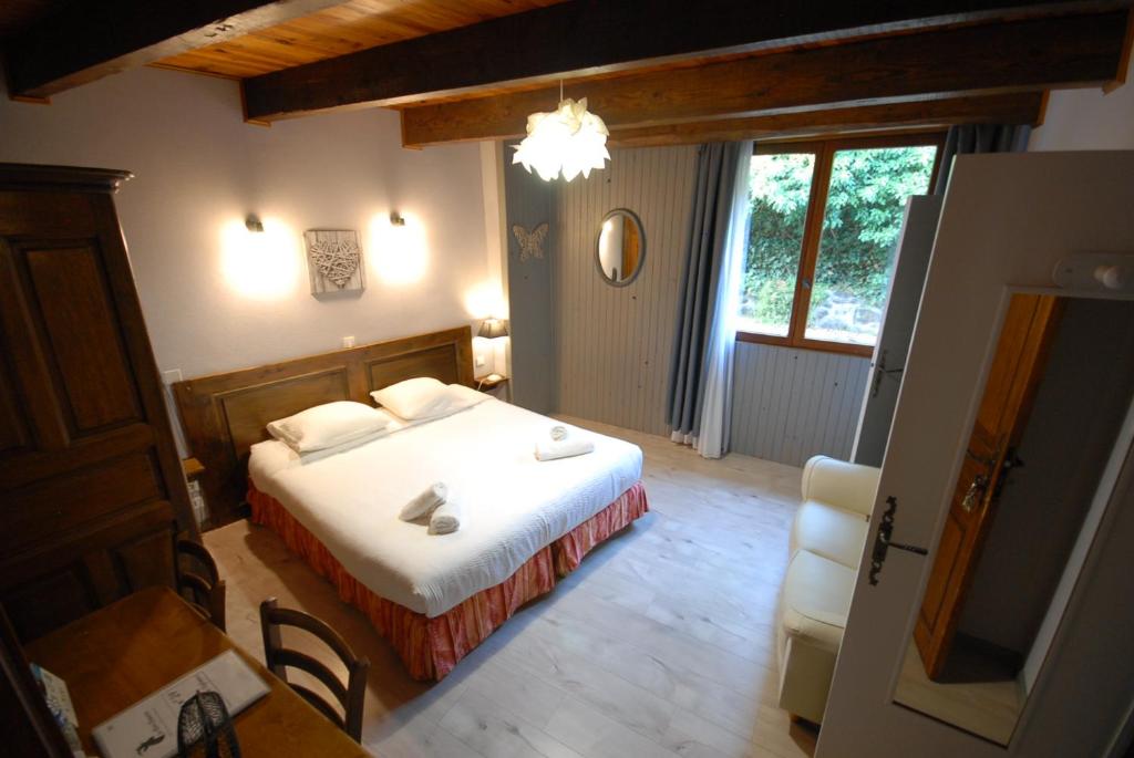 a bedroom with a bed and a table and a chair at Logis Hôtel-restaurant La Mère Biquette in Saint-Pons