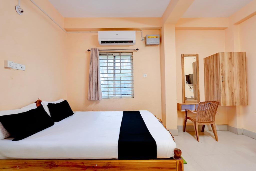 a bedroom with a large bed and a chair at Hotel O Snow White in Bhadrak