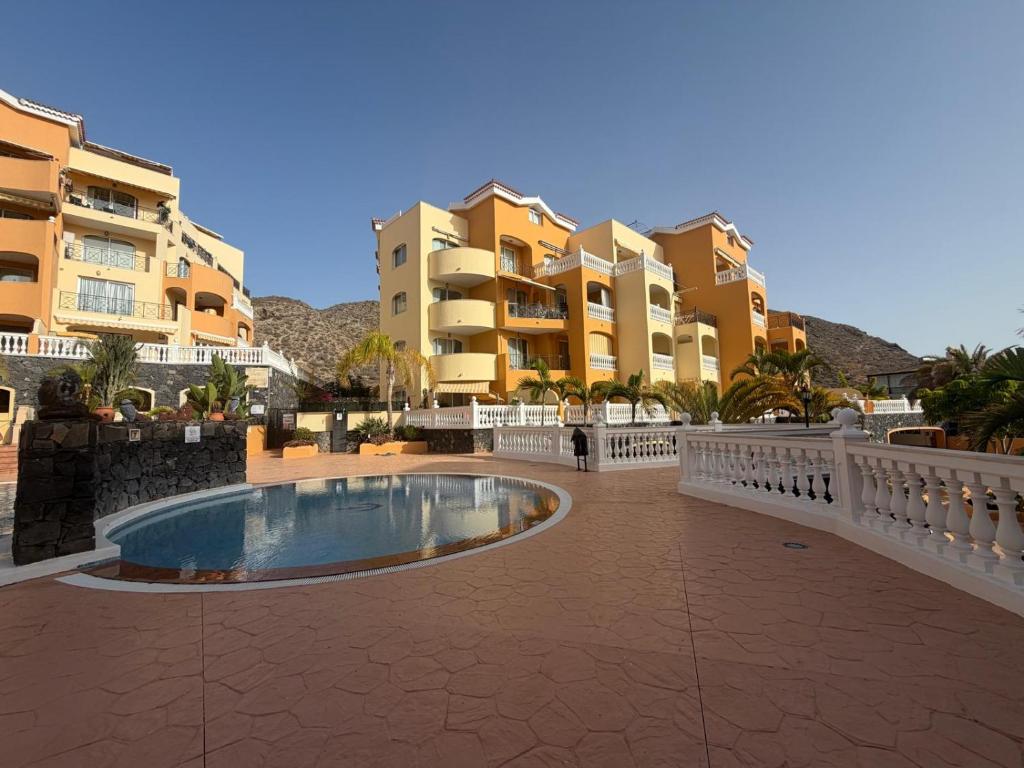 a swimming pool in a courtyard in front of some buildings at Apartamento Pargue Tropical in Los Cristianos