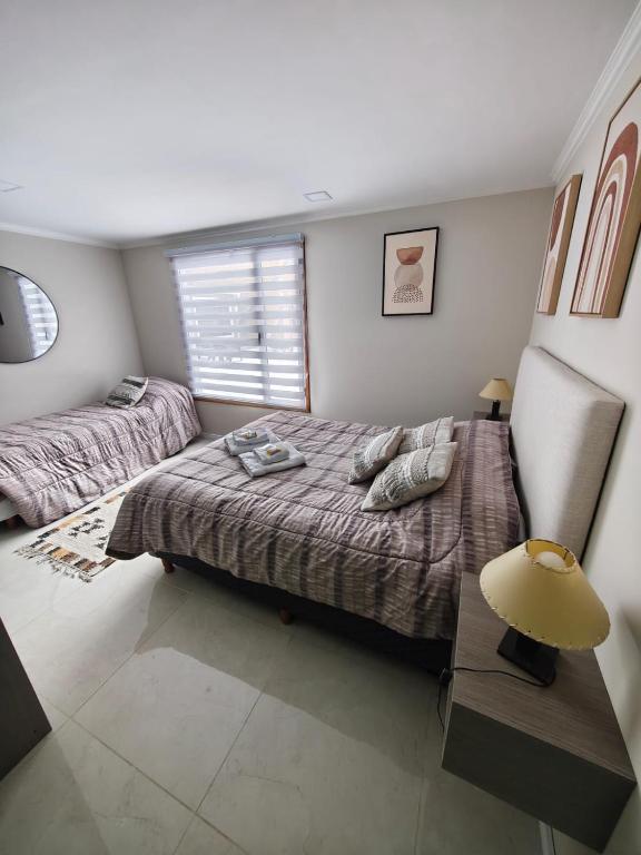 a bedroom with two beds and a lamp and a window at Departamentos Turísticos MD in El Calafate