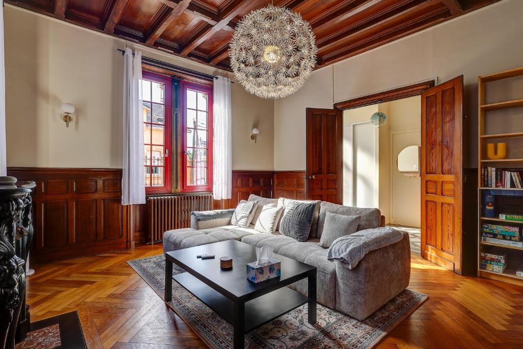 a living room with a couch and a chandelier at La Maison des Prés - Maison bourgeoise de 1890 in Montceau-les-Mines