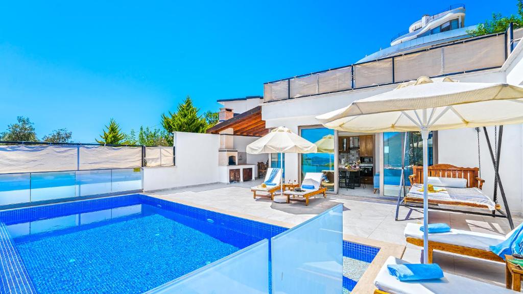a swimming pool with chairs and an umbrella next to a house at Secluded Sea-View Family Escape Villa Bella 3 Lale in Üzümlü