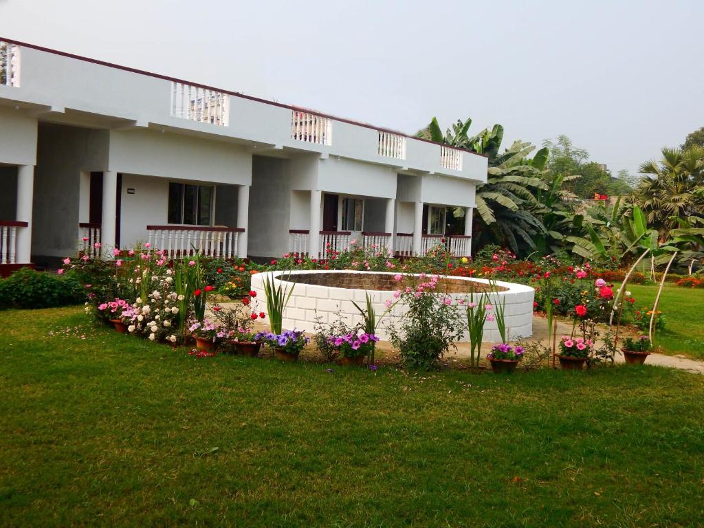 a building with a bunch of flowers in a yard at Samriddhi Banquet Garden & Resorts in Baharampur