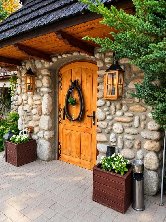 a stone house with a wooden door with areath on it at Willa Wojciechówka in Kościelisko