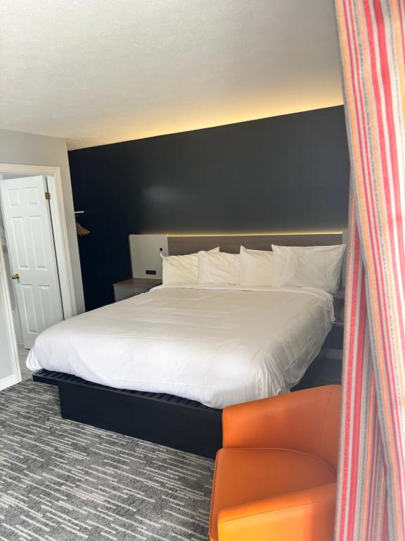 a bedroom with a large white bed and a chair at Hilltop Motel & Restaurant in Grand Falls