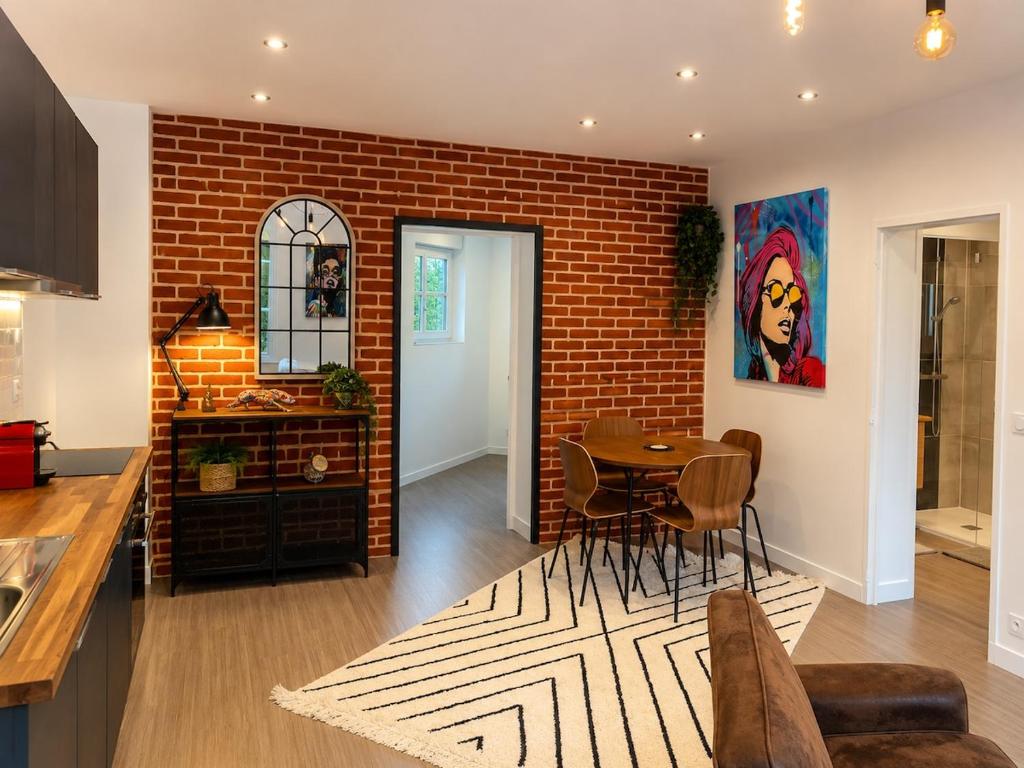 a kitchen and dining room with a brick wall at Brick - Loft design avec parking privé in Saint-Désir