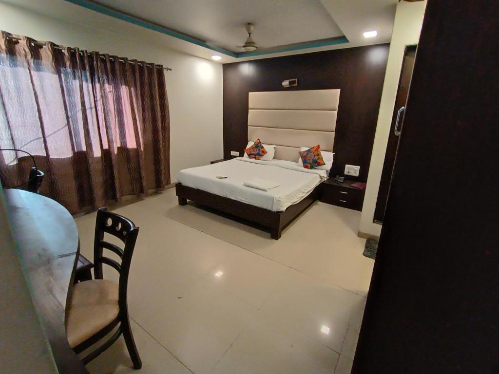 a bedroom with a bed and a table and chairs at Crown Hotel Aadoree - Near Mumbai Airport, BKC Visa Consultant , Jio Convention Centre in Mumbai