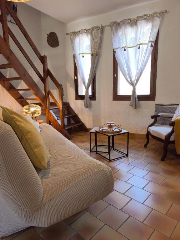 a living room with a couch and two windows at Six Duplex à la montagne POMPIERY in Seyne