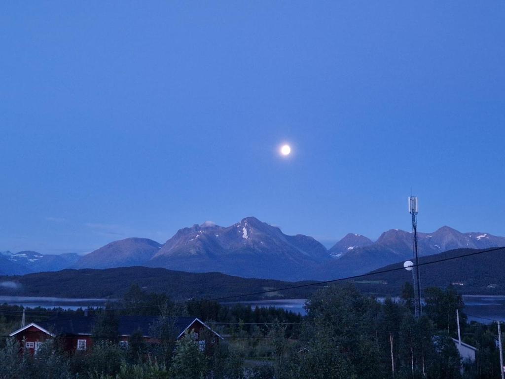 a moon in the sky over a mountain range at Mountainview apartment in Storsteinnes