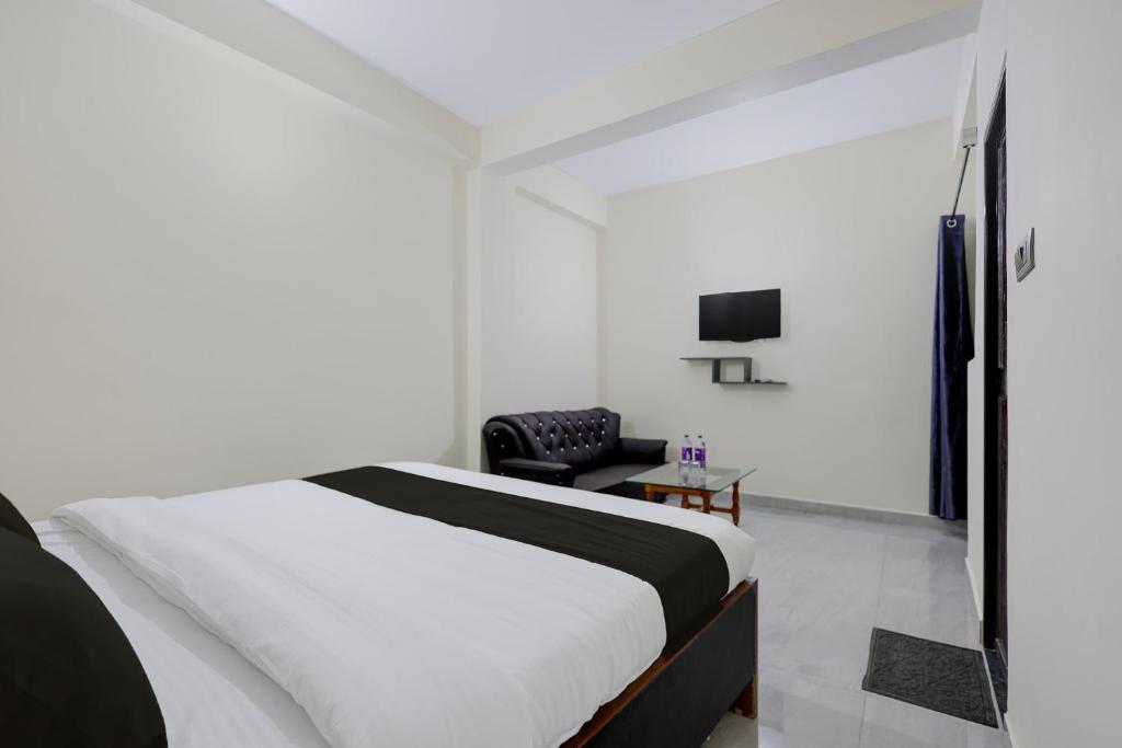 a white bedroom with a bed and a chair at Hotel O VIP Inn in Bankipur