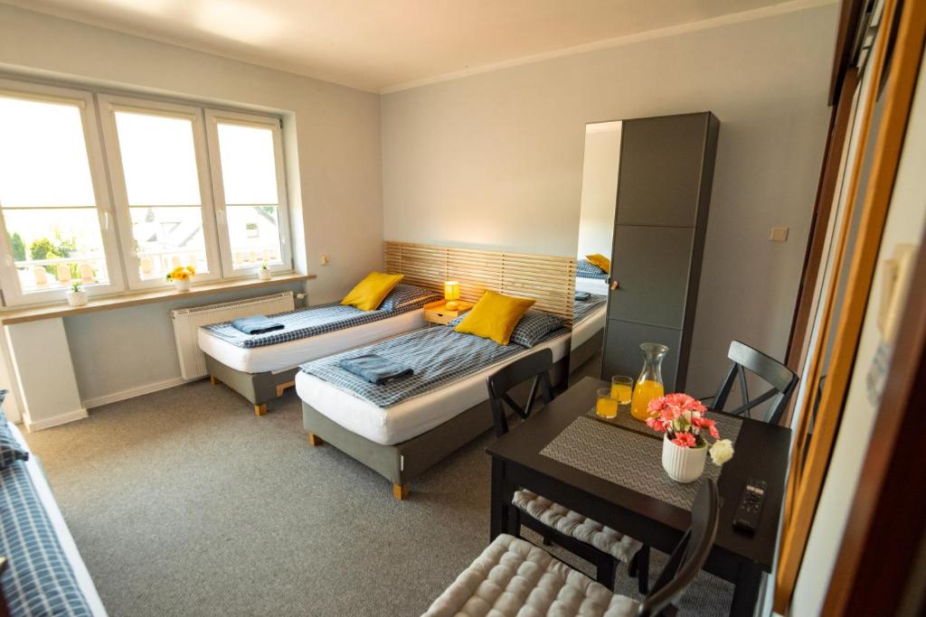 a small room with two beds and a table at Dom na Folwarku POKOJE I APARTAMENTY, BEZPŁATNY ZAMYKANY PARKING NA TERENIE POSESJI in Kielce