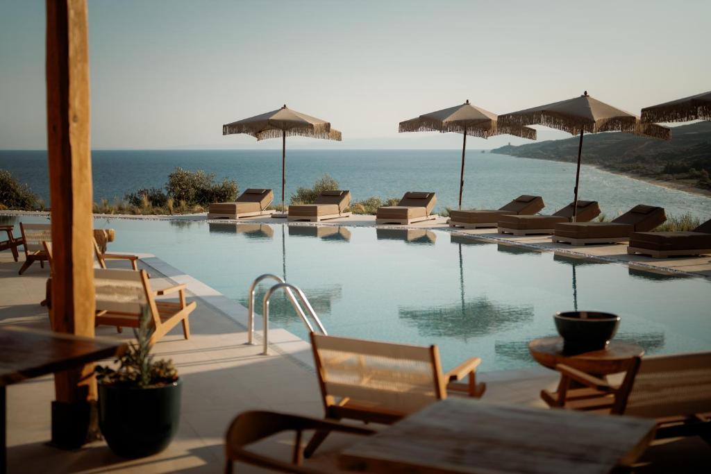 a swimming pool with chairs and umbrellas at Manas Villas in Elaiokhórion