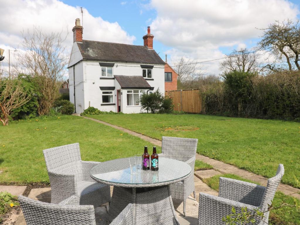 a table and chairs with bottles on it in a yard at Hops Cottage in Ashbourne