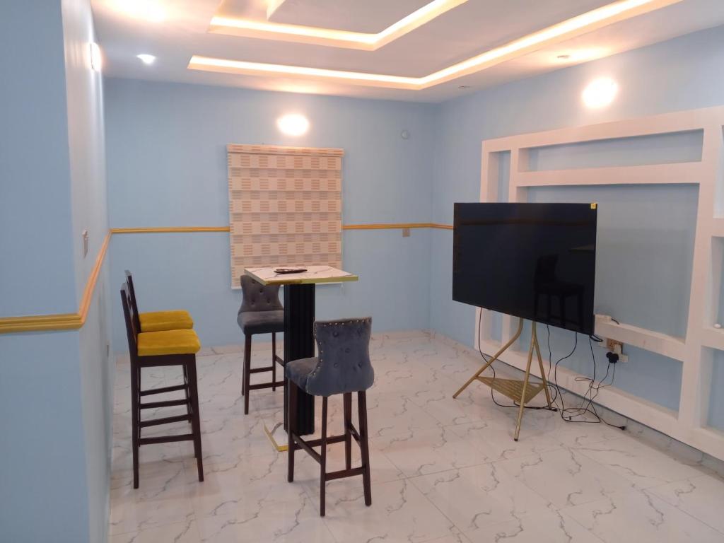 a room with a tv and some chairs and a table at Four bedroom duplex in Lagos