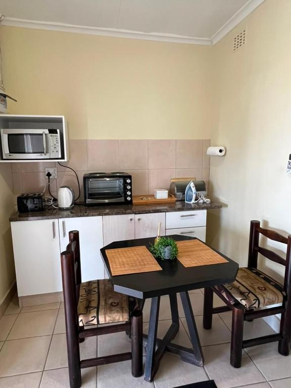 a kitchen with a table and chairs and a microwave at Dube Villa in KwaDukuza