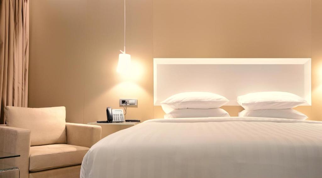 een slaapkamer met een wit bed en een stoel bij Saz City Life Boutique Hotel in Ioannina