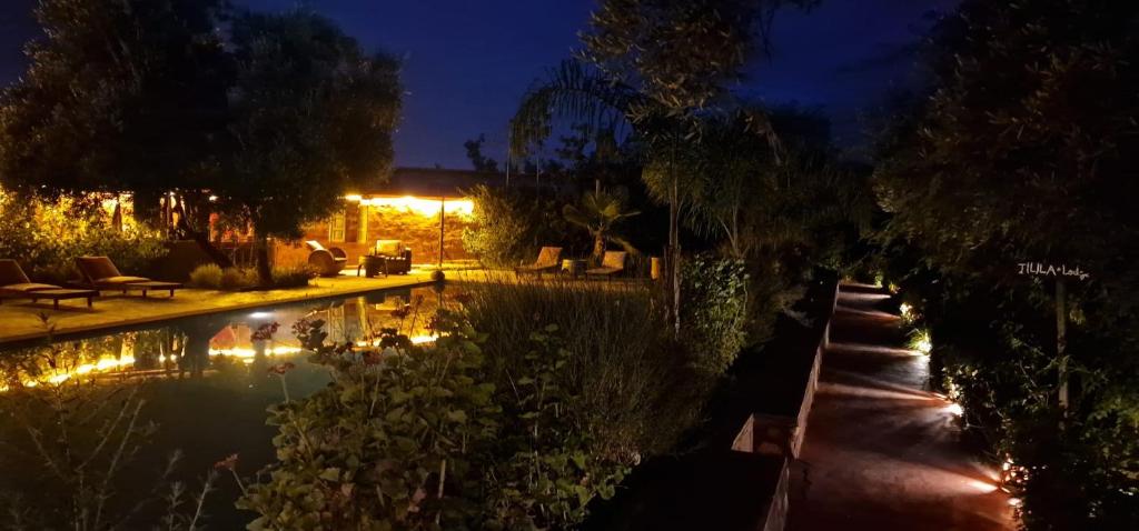 a swimming pool in a garden at night at Ecolodge Dar bouhouta in Tahannout