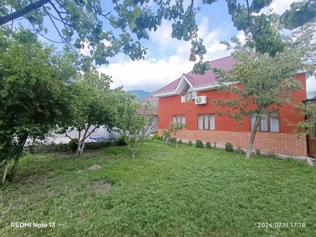 a red house with a lawn in front of it at Sheki Dream House in Sheki