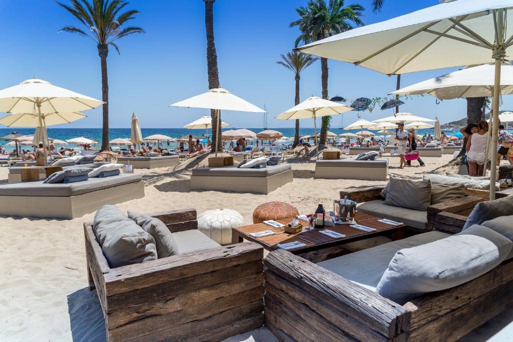 a beach with chairs and tables and umbrellas at Apt in Playa den Bossa next Ushuaia, beachfront, reliable host in Ibiza Town