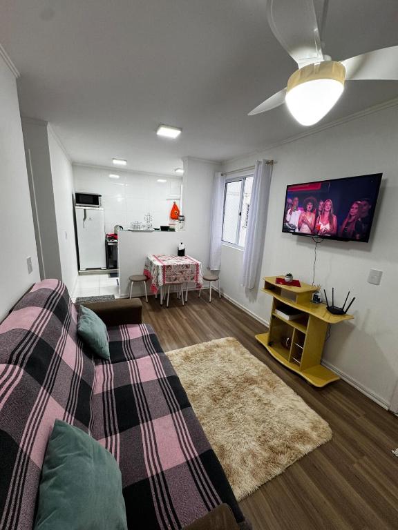 a living room with a bed and a tv on the wall at Apartamento in Campo Largo