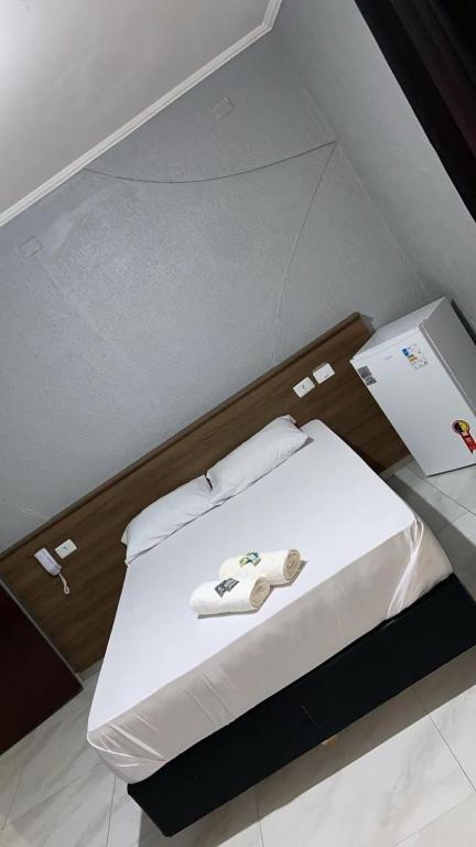 a room with a bed with white sheets and a table at Hotel Matarazzo in São Paulo