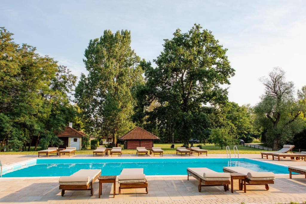 a pool with tables and chairs next to a park at Izletište Ružić in Mrčajevci