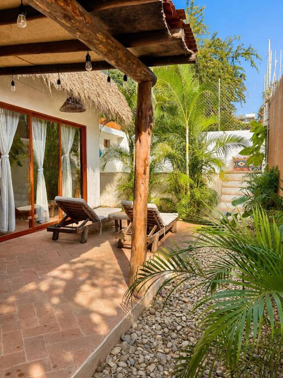a patio with two chairs and a umbrella at Casa Coconut in Puerto Escondido