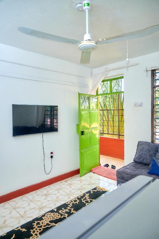 a living room with a green door and a tv at Tranquil Terrace Cottages Diani in Diani Beach