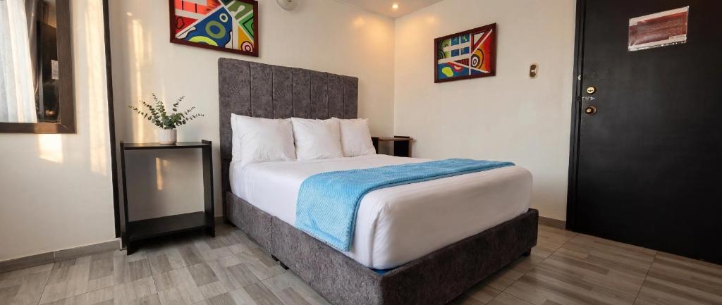 a bedroom with a large bed with a blue blanket at Hotel el Duque Internacional, Bogotá in Bogotá