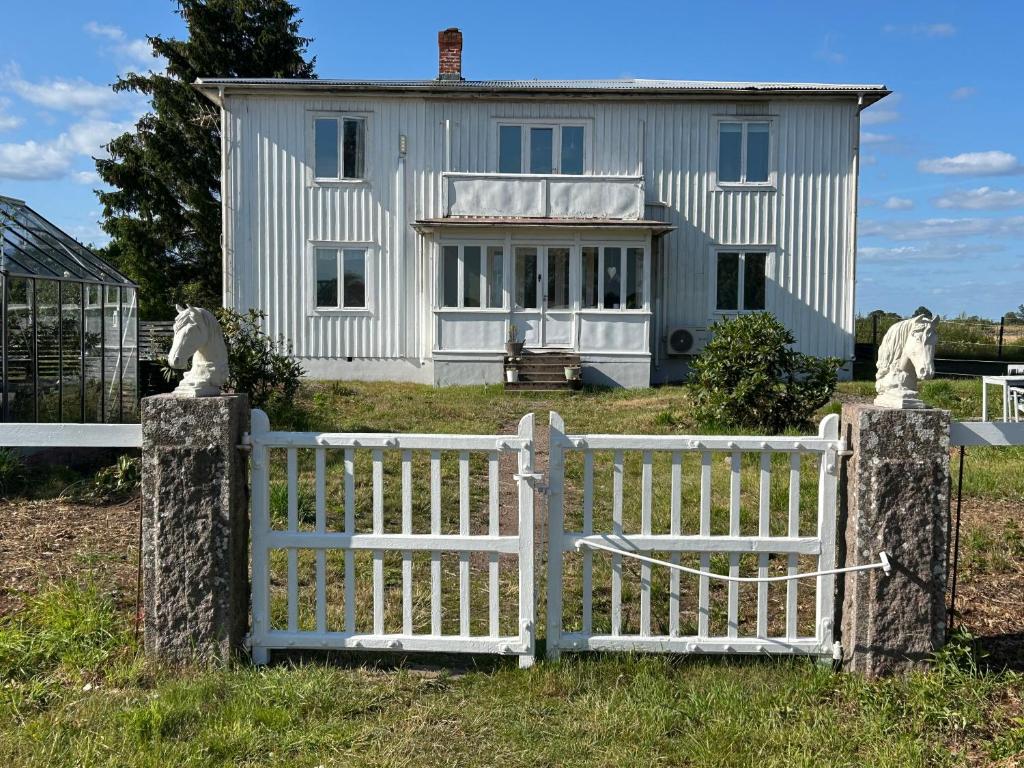 a white fence in front of a white house at Bockekulla Gård in Bergkvara