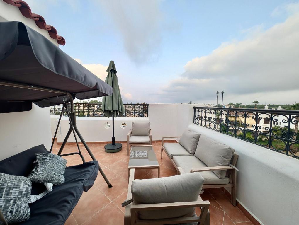 a balcony with a couch and an umbrella and a table at Andalucia Family-Only Aparthotel in Cabo Negro