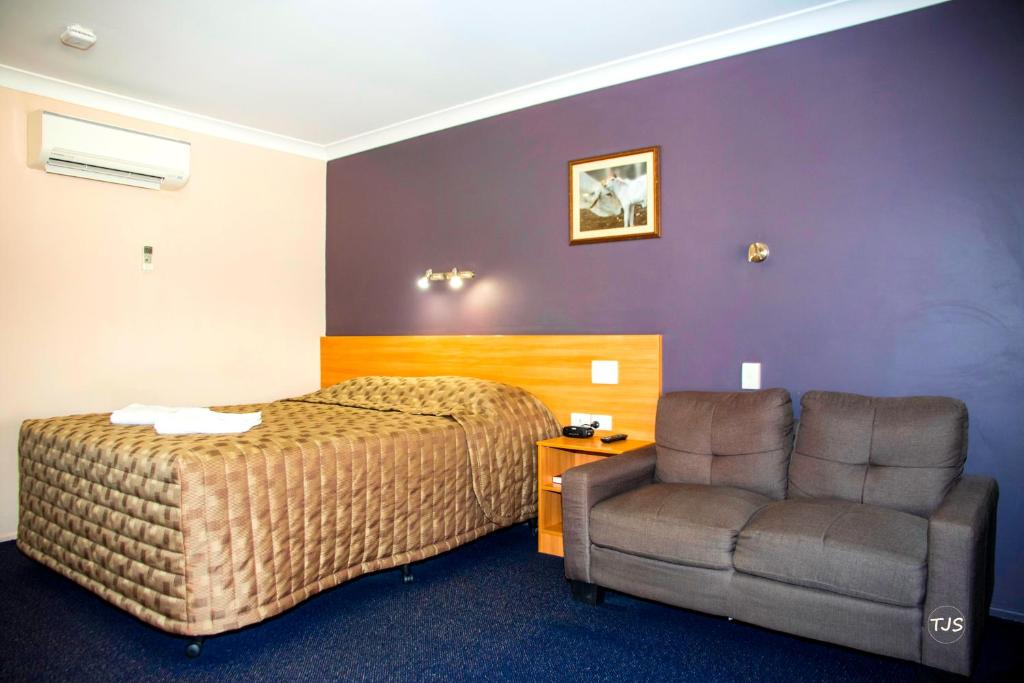 a hotel room with a bed and a chair at SunPalms Motel in Rockhampton