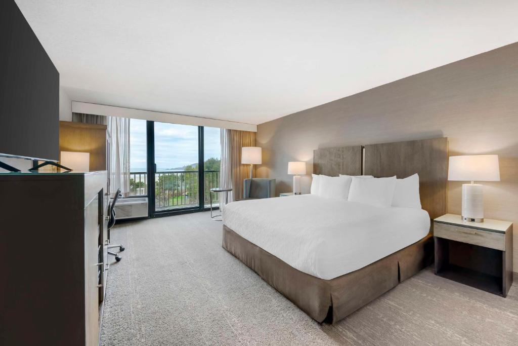 a hotel room with a bed and a balcony at Best Western Plus Agate Beach Inn in Newport