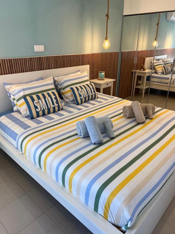a large bed with colorful striped sheets and pillows at SummerHouse - Holiday place! in Portimão