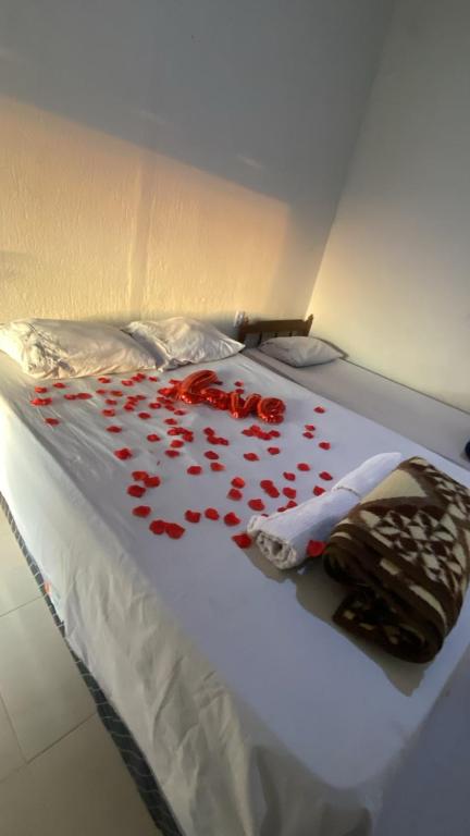 a bed with red rose petals on it at Pousada flores de ipê in Capitólio