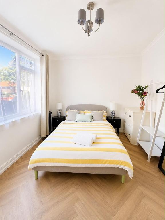 a white bedroom with a large bed with yellow and white stripes at At Number 36 in London