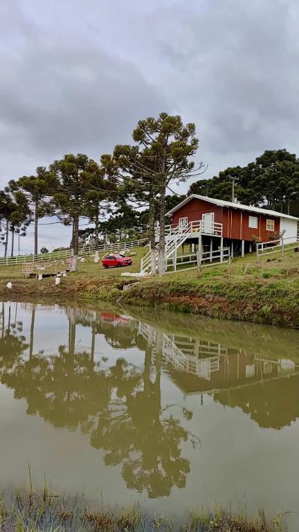 a house sitting next to a body of water at Casa de Campo Bella Vista in Urupema