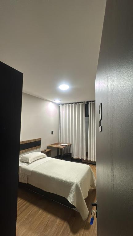 a bedroom with a bed and a table in it at Quarto Personalizado Individual aconchegante novo no coração da cidade -Ufla- restaurantes e padaria in Lavras