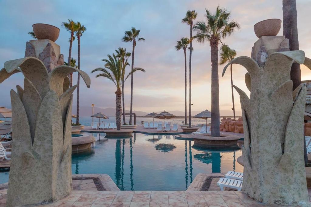 a pool at a resort with palm trees at Naya homes: The estero beach. in Ensenada