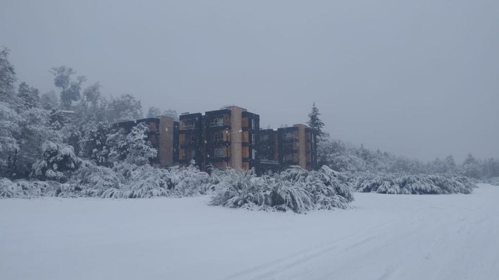 a building covered in snow next to a snow covered field at Viento azul in Villa La Angostura