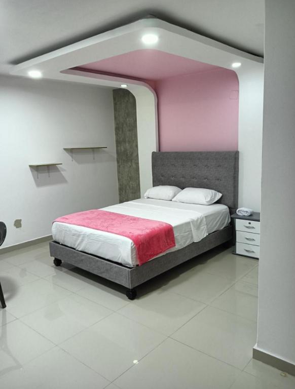 a bedroom with a large bed with a pink ceiling at Hotel Pasarela in Cali