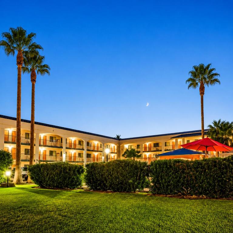 a hotel with palm trees in front of a building at TrueStay Inn in Bakersfield
